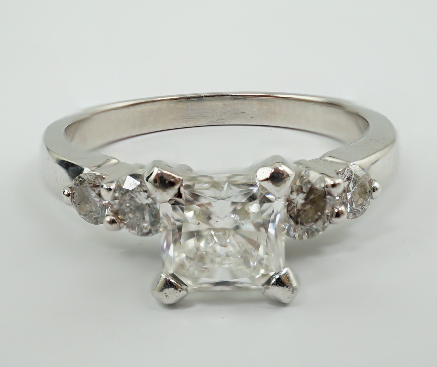 A modern 14k white gold and single stone diamond set ring, with four stone diamond set shoulders